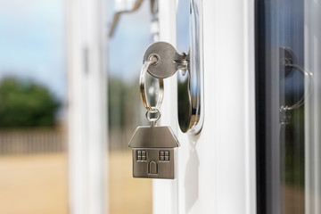 House key on a house shaped silver keyring in the lock of a door