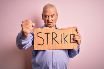 Middle age man asking for rights holding banner with strike message over pink background annoyed and frustrated shouting with anger, crazy and yelling with raised hand, anger concept