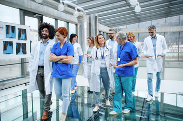 Front view of group of doctors walking in corridor on conference.
