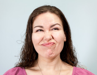 Dislike and discontent on the face of an adult woman, portrait on grey background, emotions series.