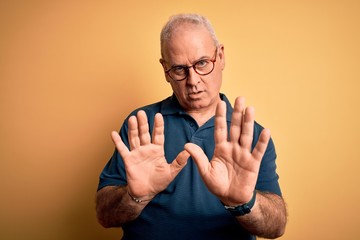 Middle age handsome hoary man wearing casual polo and glasses over yellow background Moving away...