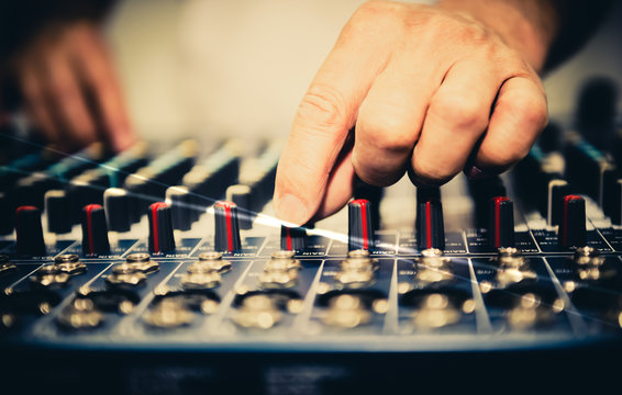 Close up images of Sound engineer Currently using the finger to hold the volome of the mixer to complete the adjustment of the music, to people and equipment for musical entertainment concept.