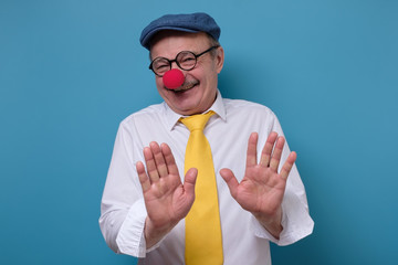 man with red nose and funny cap showing his hand as stop sign.