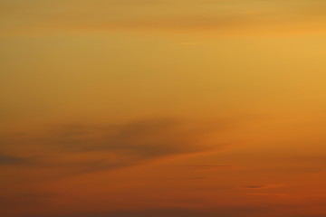 Fototapeta premium Sun below the horizon and clouds in the fiery dramatic orange sky at sunset or dawn backlit by the sun. Place for text and design.