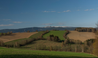 Krkonose mountains in spring sunny day with color meadows and fields