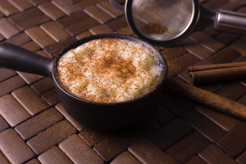 Traditional June party Brazilian dessert made of rice and condensed milk called arroz doce decorated with cinnamon in wood background
