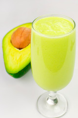 Glass of avocade cream with an open avocade isolated in white background