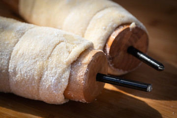 Hungarian sweet chimney cake dough rolled on baking roll. Butter and sugar coated.Two rolls