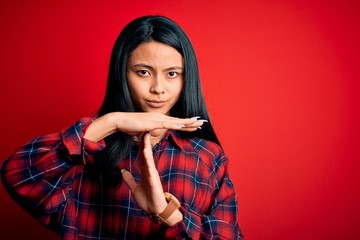 Young beautiful chinese woman wearing casual shirt over isolated red background Doing time out...