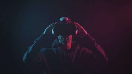 Portrait of a man in virtual reality helmet. Obscured dark face in VR goggles. Internet, darknet, gaming and cyber simulation.