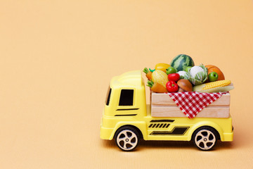peasant farm vegetables shipping. A yellow toy truck delivering fresh fruits and vegetables in a wooden box