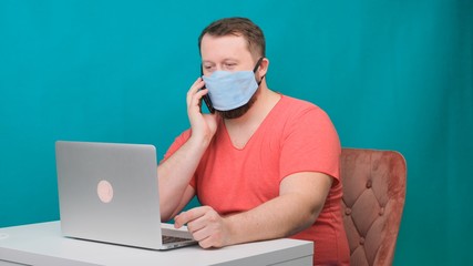 Fototapeta na wymiar Man working from home. Using a smartphone. Bearded man in a protective mask works at home.