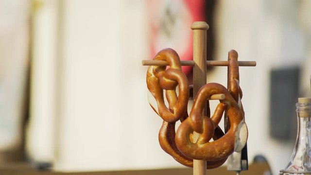 Salted pretzels put on table on wooden stand in traditional alsatian outdoor cafe at blurred background with red nazi flag. Decoration for historical film about world war