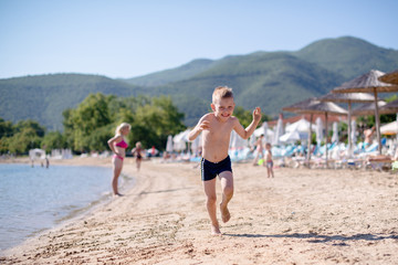 Fototapeta na wymiar Young blond boy is running on a sand