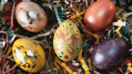 Colorful Easter eggs on stands, with paper decor of different colors in focus. Cake with icing in focus. 
With free space.