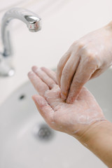 Woman washes her hands by surgical hand washing method. She washes his hands for at least 20 seconds. She washes the palm of his hand.