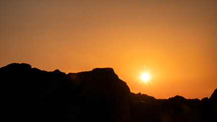 Amazing Sunset or Sunrise With Sun Over Dark Mountain Silhouette. Sunset in the orange sky