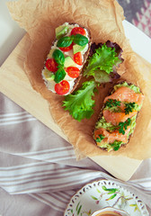 Wholegrain toast with avocado, tomato and salmon on wooden cutting board