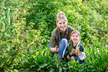 Mother and daughter in the garden harvest. A young blonde woman and a little girl with light hair. 