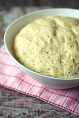 Yeast dough in a bowl. Homemade dough with herbs for bread or pizza. Baking at home.