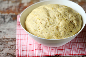 Yeast dough in a bowl. Homemade dough with herbs for bread or pizza. Baking at home.