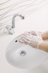 Woman washes her hands by surgical hand washing method. She washes his hands for at least 20 seconds. She is rubbing the palm of his hand.
