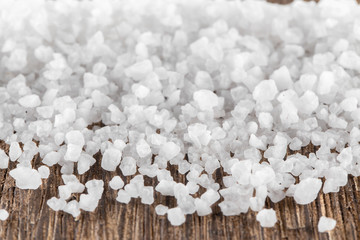 Scattered sea salt on a wooden background. Texture