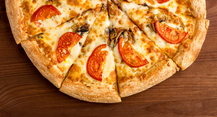 tasty pizza from tomato, cheese and aromatic mushrooms champignons on a wooden table. Top view