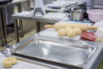 Professional chef, baker workplace with sheet, fresh dough and rolling pin for baking buns on table at cuisine of restaurant, bakery. Cooking, catering, culinary, gastronomy and food concept