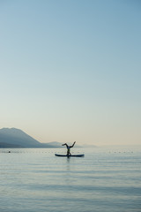 Naklejka premium Making headstand on sup board on the sea