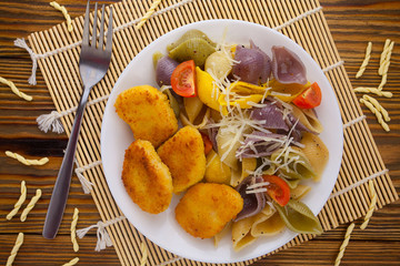 tasty appetizing pasta with chicken nuggets on white plate