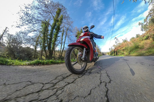Selfie de una persona conduciendo una motocicleta roja por la naturaleza