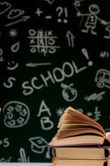 Book stack on a green blackboard background, back to school concept