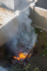 Fire coils over a burnt building. A pile of coals at the site of a burnt shed. Bright flames, flying ashes of a burning wooden building during a fire