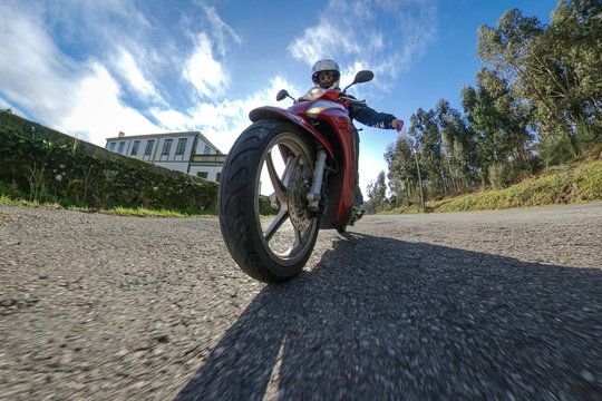 Selfie de una persona conduciendo una motocicleta roja por la naturaleza