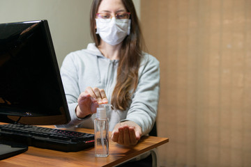 Business woman working from home wearing protective mask. Cleaning her hands with sanitizer gel.