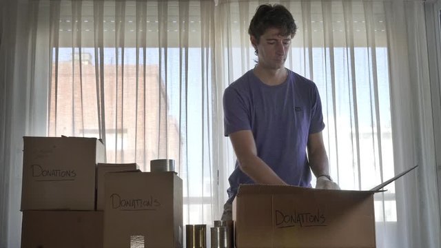 Man preparing box of donations with canned food