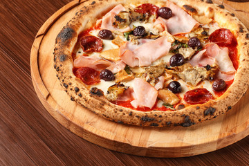 Pontremolina. Hot Italian pizza with Piennolo tomatoes, turkey ham, artichokes, oregano and salami. Original recipe. Pizza on wooden background