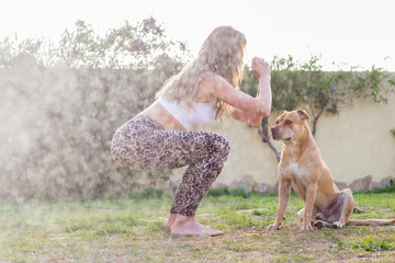 Young beautiful woman practicing yoga with her dog outdoors - 341072592