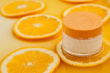Cosmetic jar with natural energy vitamin skin care. Cosmetic cream on an orange background.
