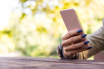 Woman using her Mobile Phone outdoor. Woman typing phone message on social network