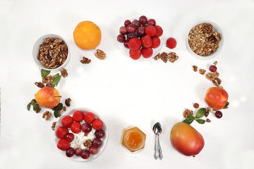 Strawberry yogurt, granola, cottage cheese, honey, mango, strawberries and grapes on a light table. The concept of healthy and natural food. Useful breakfast, food for children, selective focus,