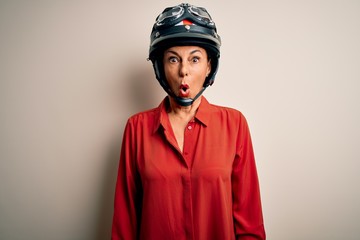 Middle age motorcyclist woman wearing motorcycle helmet over isolated white background afraid and shocked with surprise expression, fear and excited face.