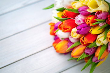 Colorful bouquet of tulips on white wooden background. Spring flowers. Greeting card with copy space for Valentine's Day, Woman's Day and Mother's Day. Top view