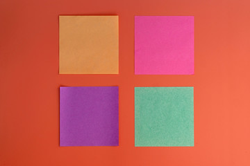 Colored square leaflets for reminders top view. Reminder sticky note on red background, empty space for text. office sticker pink, yellow, green, purple.