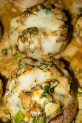 Mushrooms baked in the oven with cheese, green onions and dill. Close up.