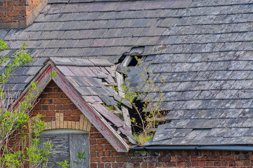 Damaged slate roof tiles on a pitched roof © russell102