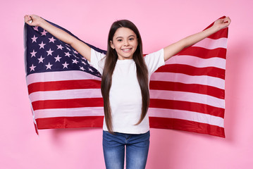 The American Dream. July 4, USA. beautiful girl in a white T-shirt with the American flag, on a pink background.