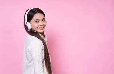 Elegant funny beautiful emotional young lady in headphones,in a white T-shirt on a pink background.