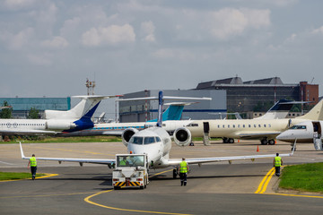 Airport taxi tug in front of plane parking with business jets